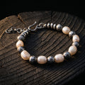 White baroque pearls alternating with darkened hand-hammered 925 sterling silver beads, with a hammered S-hook and extender chain, on a dark tree stump