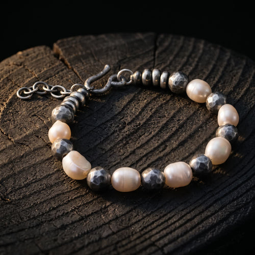 White baroque pearls alternating with darkened hand-hammered 925 sterling silver beads, with a hammered S-hook and extender chain, on a dark tree stump