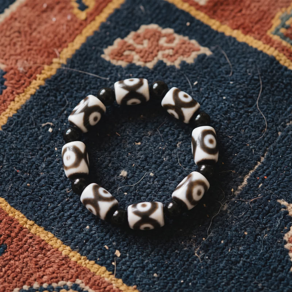 Bracelet of white agate dzi beads with brown eye patterns and black agate beads on an indigo Tibetan khaden rug