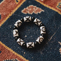 Bracelet of white agate dzi beads with brown eye patterns and black agate beads on an indigo Tibetan khaden rug
