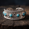 Close-up of an adjustable 925 sterling silver openwork ring with a single row of small blue-green stones set in a six-pointed star lattice, on a dark wooden stump
