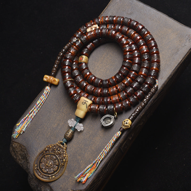 Supplier photo of the yak bone 108 mala with nine-palace pendant on a dark stone block