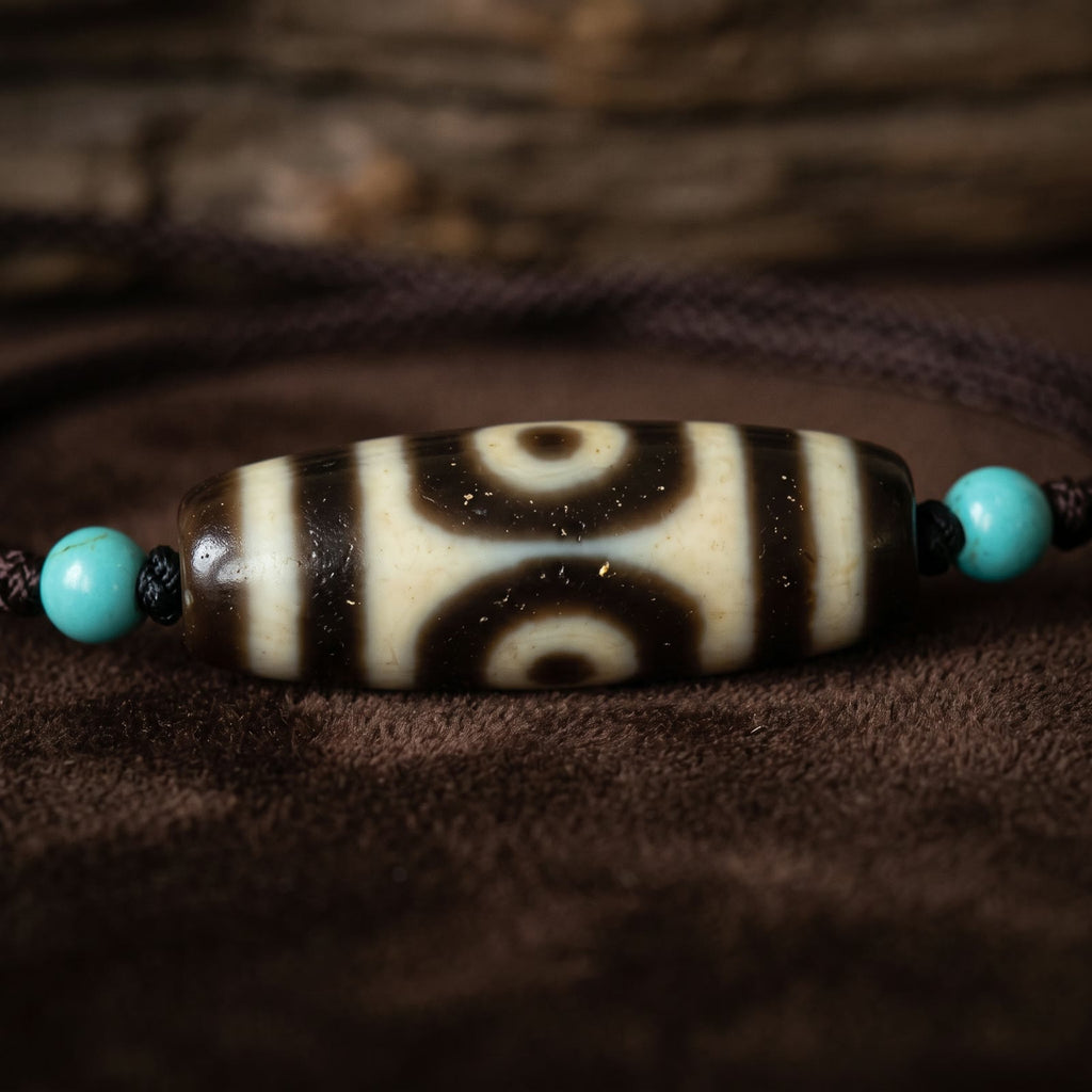 Macro close-up of the agate dzi bead showing its two eyes, ivory and deep brown bands, on dark brown velvet