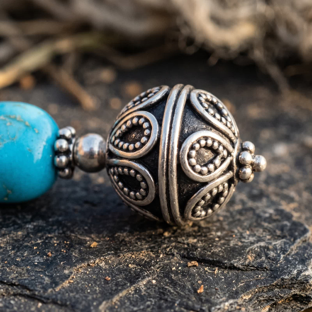 Close-up of the antiqued silvery filigree ball with granulated petals, scroll loops and darkened recesses