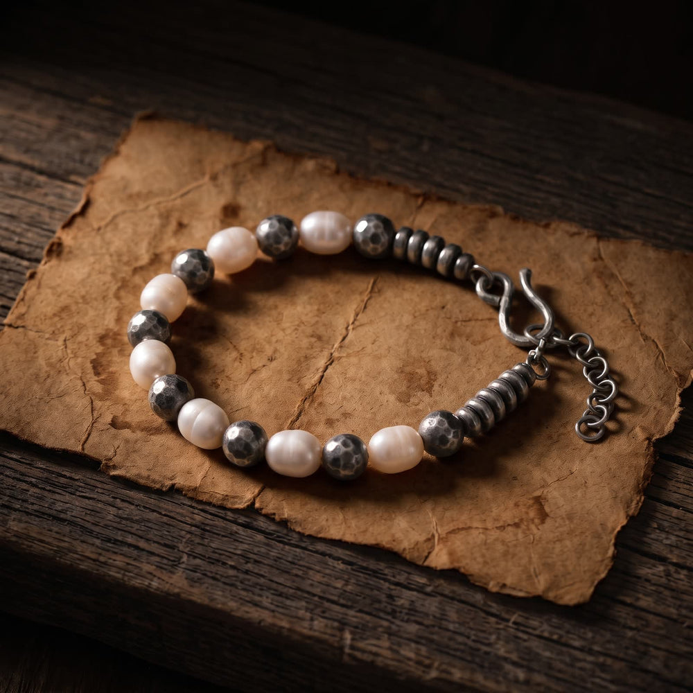 Pearl and hammered sterling silver bead bracelet laid on aged brown paper over an old dark wooden plank