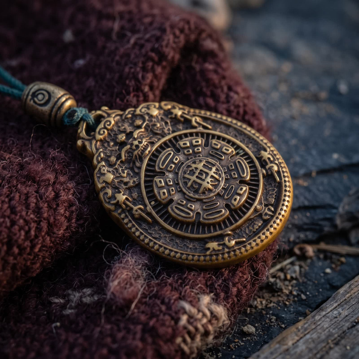 Close-up of the oval nine-palace pendant: a nine-square grid inside a ring of eight trigram symbols, on maroon wool