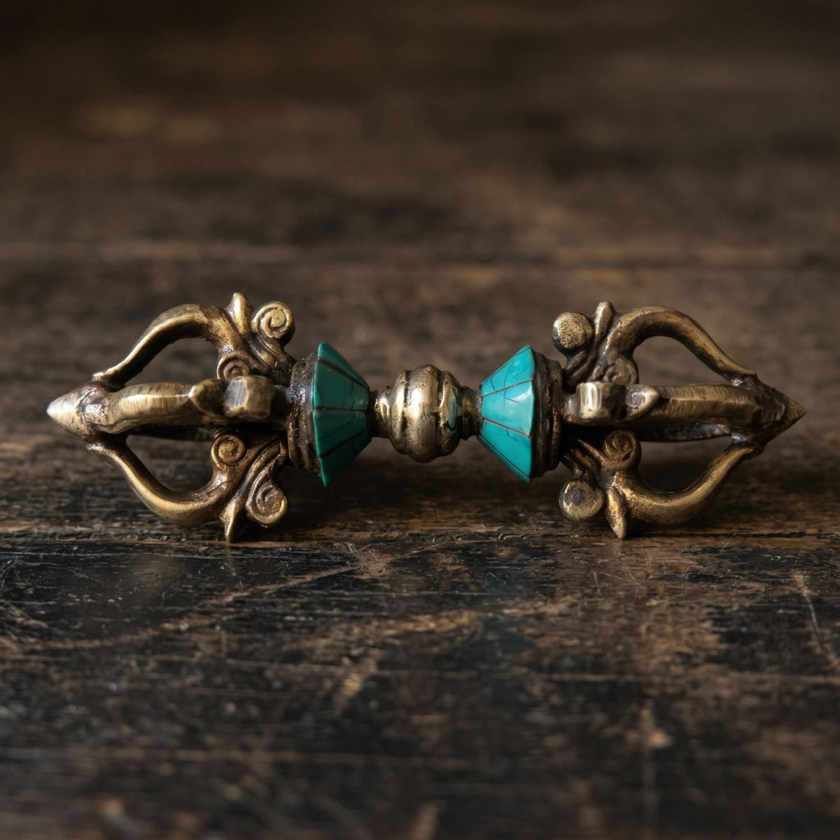 Side view of the vajra showing both open five-pronged ends with cloud-scroll roots, two blue-green inlay cones and the silvery center knob