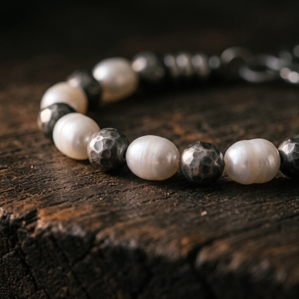 Close-up of white pearls and round hammered silver beads with a darkened finish, every hammer mark visible