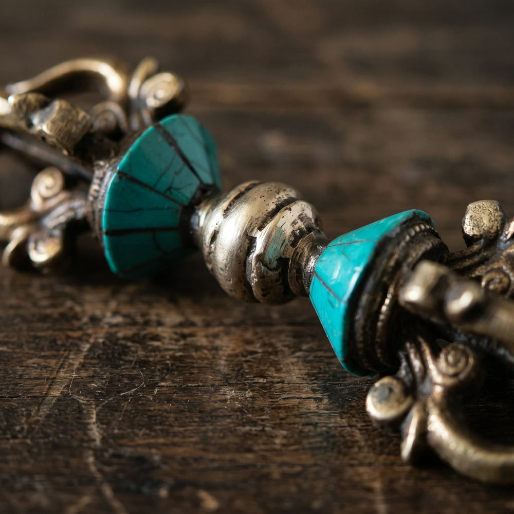 Close-up of the blue-green inlay panels with dark seams and the twisted silvery center knob of the vajra