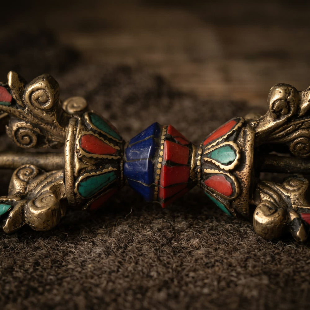 Close-up of the lotus cups and center grip of the vajra, with red, blue-green and deep blue inlay outlined in raised golden lines
