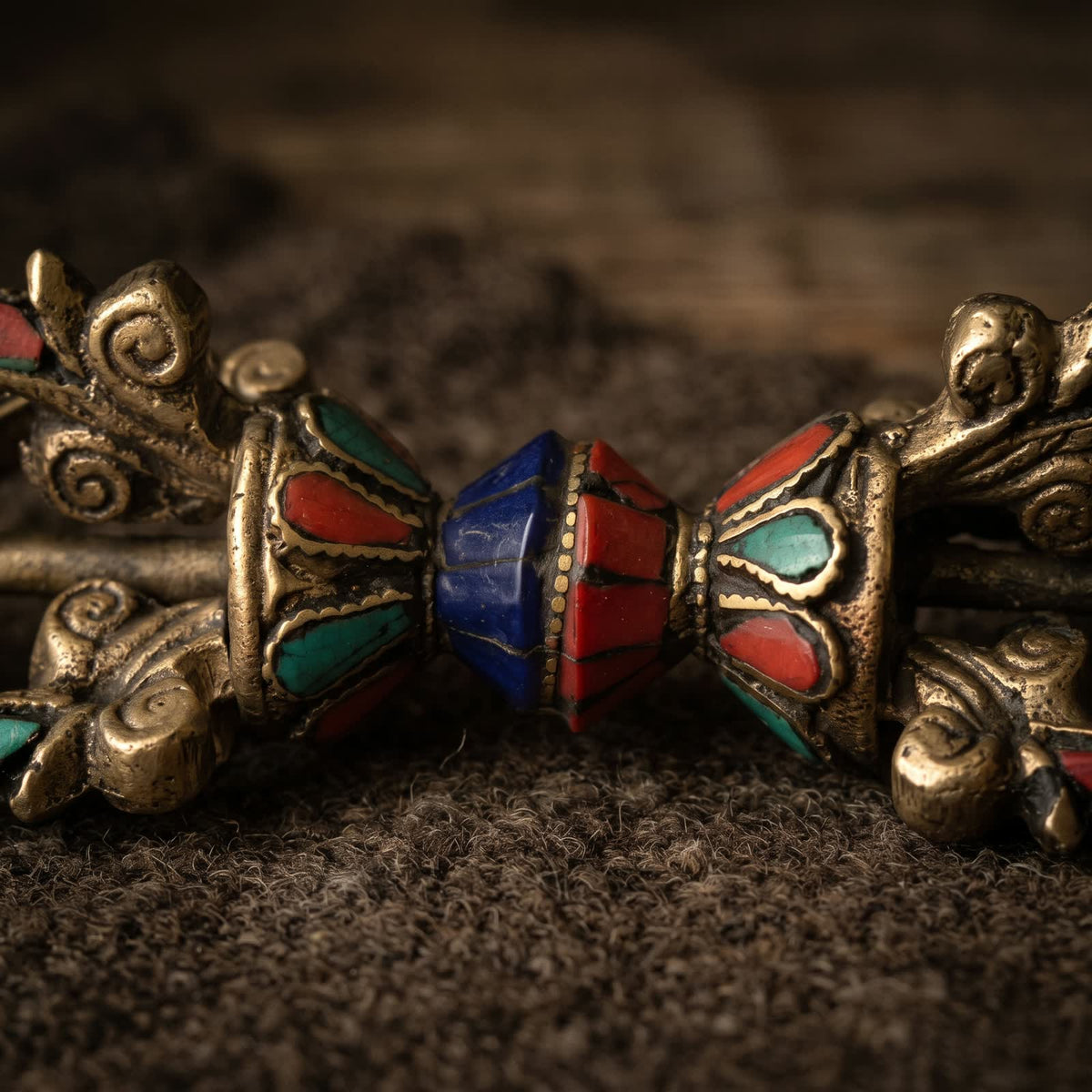 Close-up of the lotus cups and center grip of the vajra, with red, blue-green and deep blue inlay outlined in raised golden lines