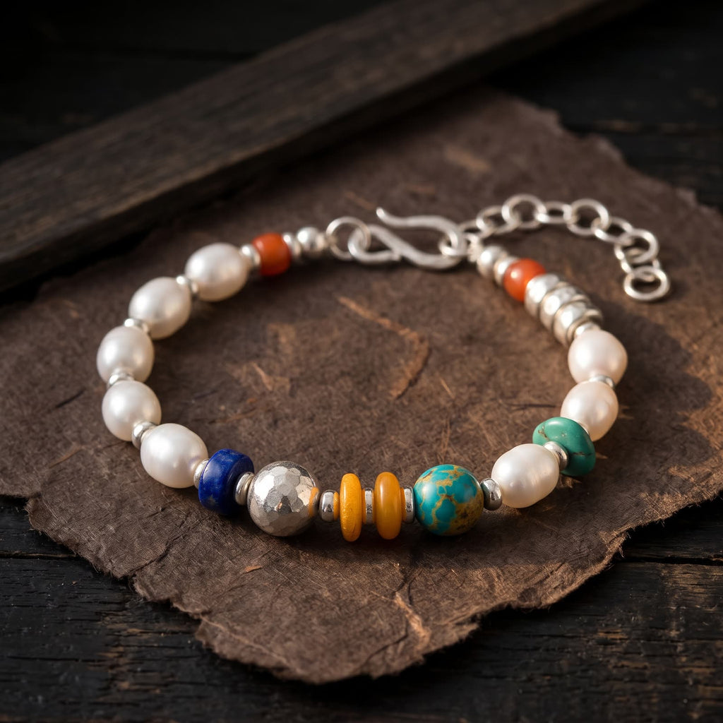 Pearl and mixed bead bracelet on a sheet of dark handmade paper on a dark wooden table in low warm side light