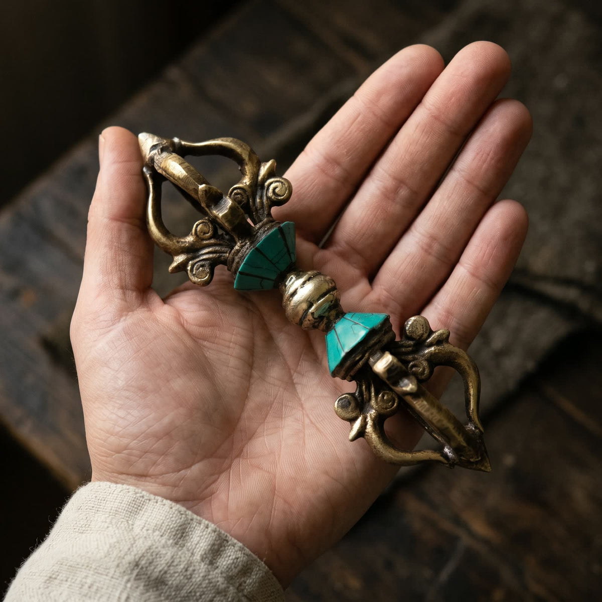 Open palm holding the vajra with blue-green inlay to show its size, about 15.5 cm long