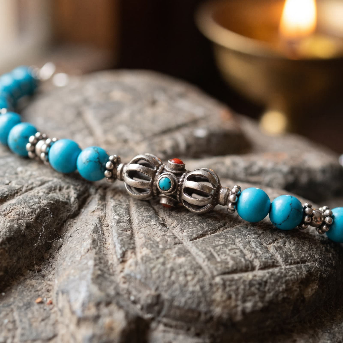 Close-up of the openwork silver vajra with small turquoise and red insets, flanked by small silver spacers and blue turquoise beads