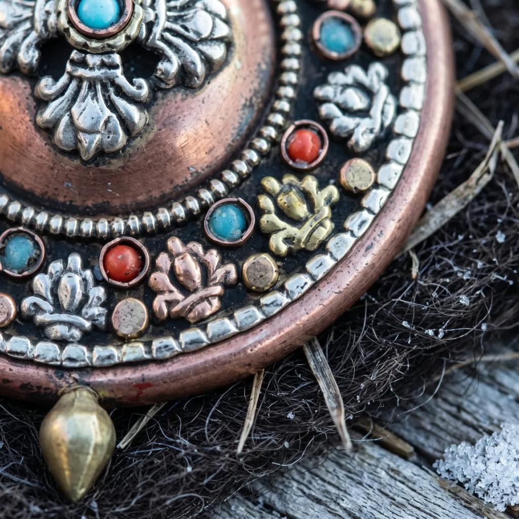 Close-up of silvery, golden and copper-red lotus appliqués alternating with red stones and stabilized turquoise on the copper gau box