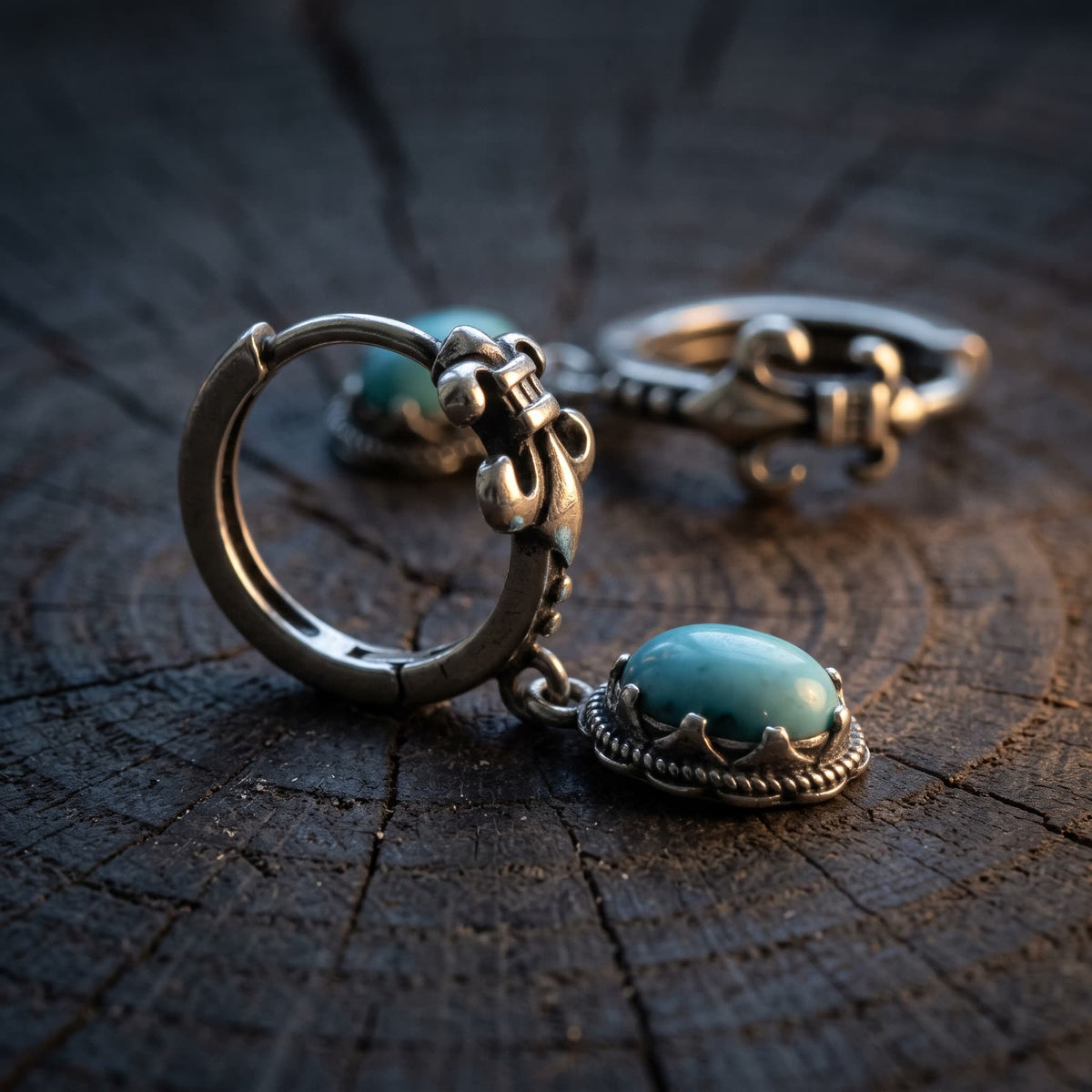 Side view of a fleur-de-lis hoop earring showing the hinged hoop and the depth of the turquoise drop