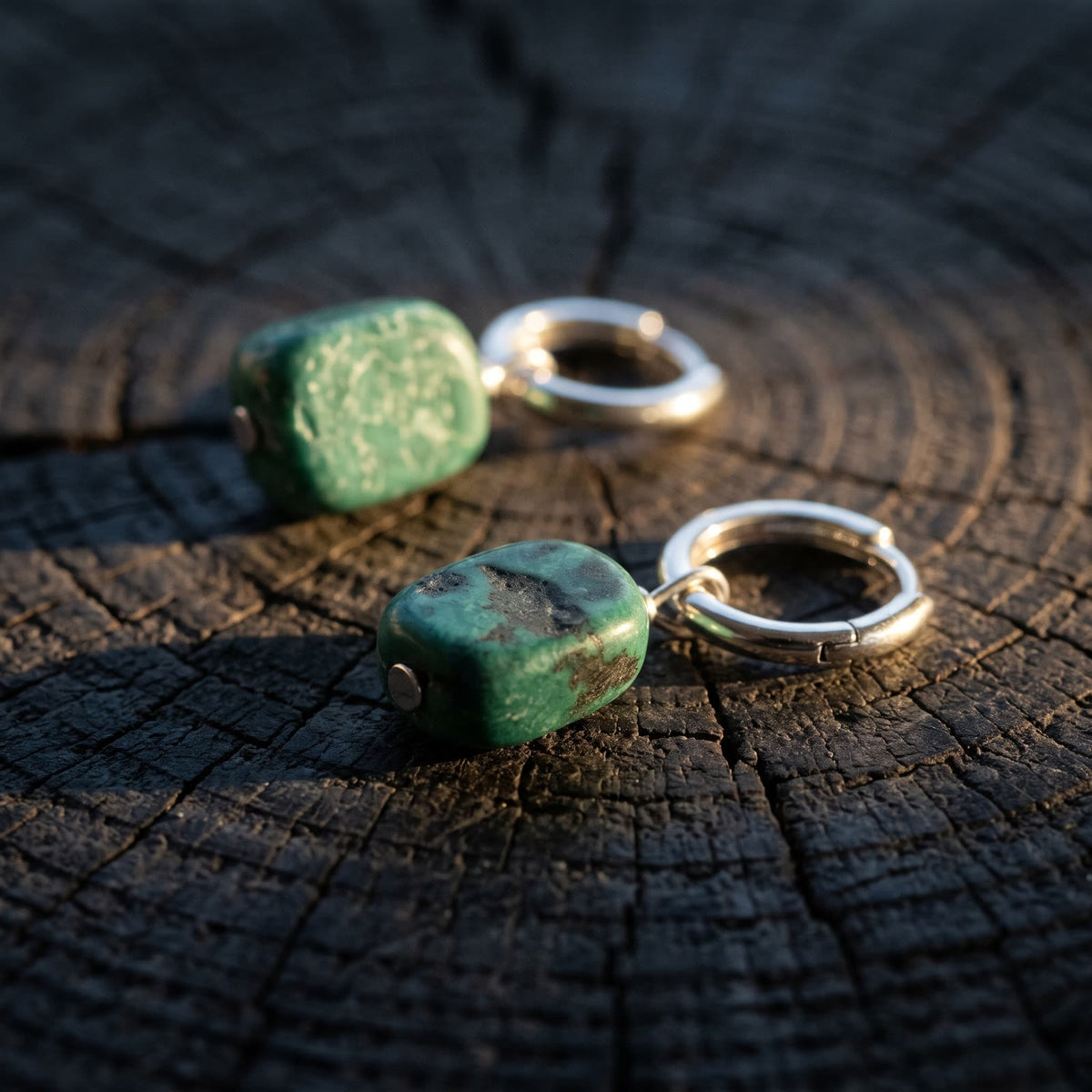 Side view of a green stone hoop earring showing the stone's thickness and the hoop hinge