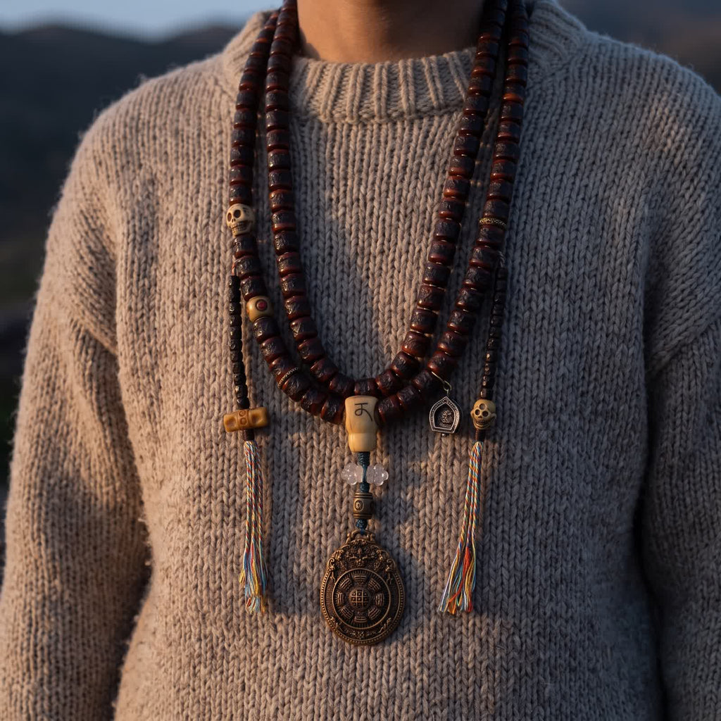 Yak bone mala worn doubled over an oatmeal wool sweater, the nine-palace pendant and tasselled counters at the chest