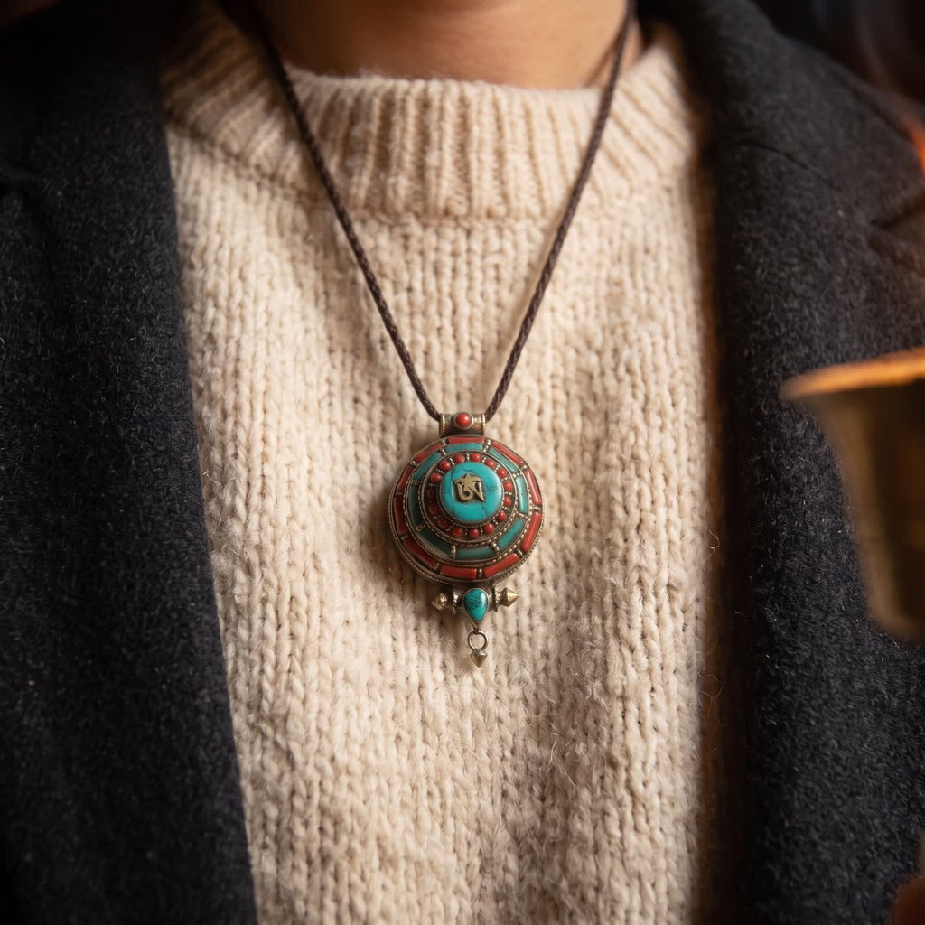 Tiered Om gau box pendant worn on a dark cord over a cream wool sweater