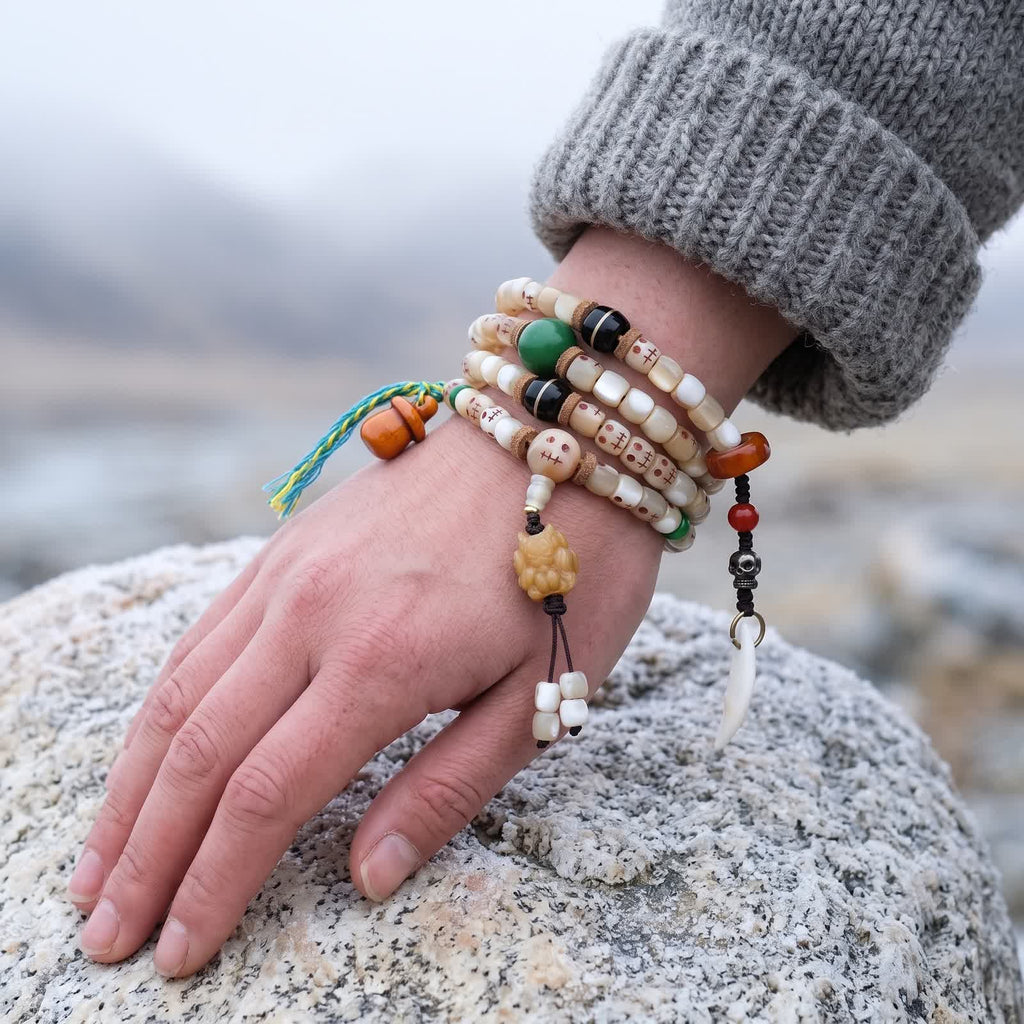 Fish bone skull-face mala wrapped four times around a woman's wrist, carved pendant and charms hanging beside the hand