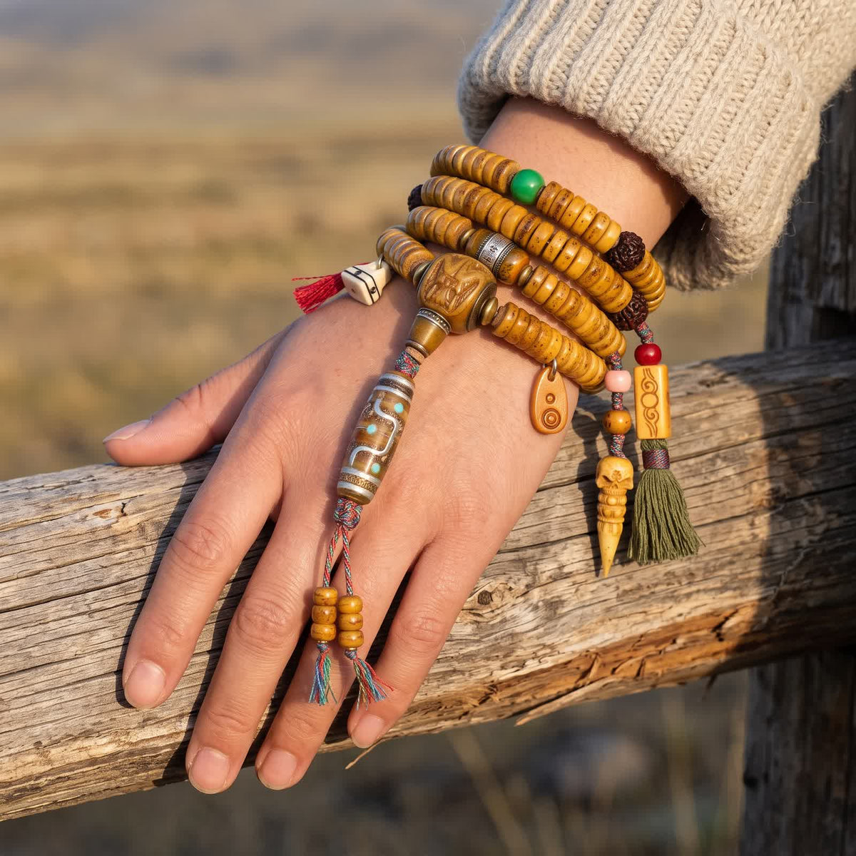 Yak bone disc mala wrapped three times around a woman's wrist, the bone dzi-pattern bead and tasselled counters hanging beside the hand