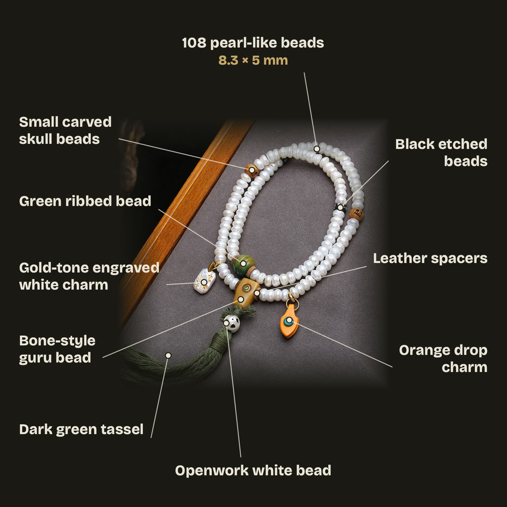 Bead guide: 108 pearl-white beads 8.3 × 5 mm, squared guru bead, green ribbed bead, orange drop charm, openwork white bead, golden engraved white charm, small carved skull beads, black etched beads, leather spacers and dark green tassel