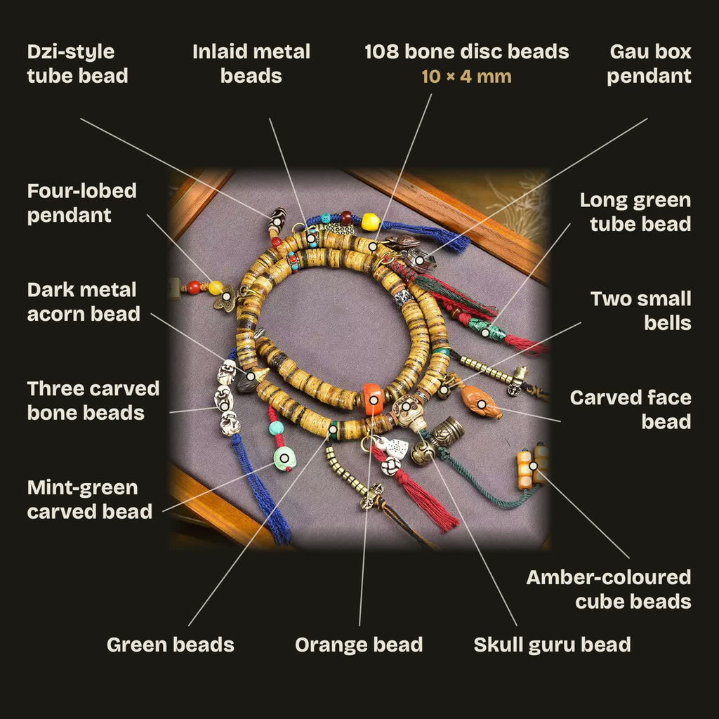 Bead guide: 108 bone disc beads 10 × 4 mm; skull guru bead, orange bead, green beads, inlaid metal beads, dark metal acorn bead, dzi-pattern tube bead, four-lobed pendant, gau box pendant, three carved bone beads, mint-green carved bead, long green tube bead, two small bells, carved face bead and honey-orange cube beads