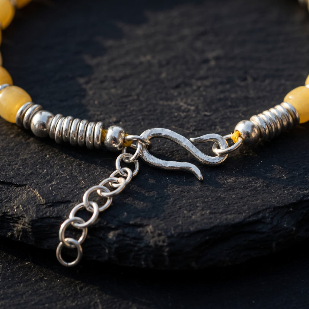 Close-up of the hand-hammered 925 sterling silver S-hook clasp, silver rondelle stacks and extender chain on black slate