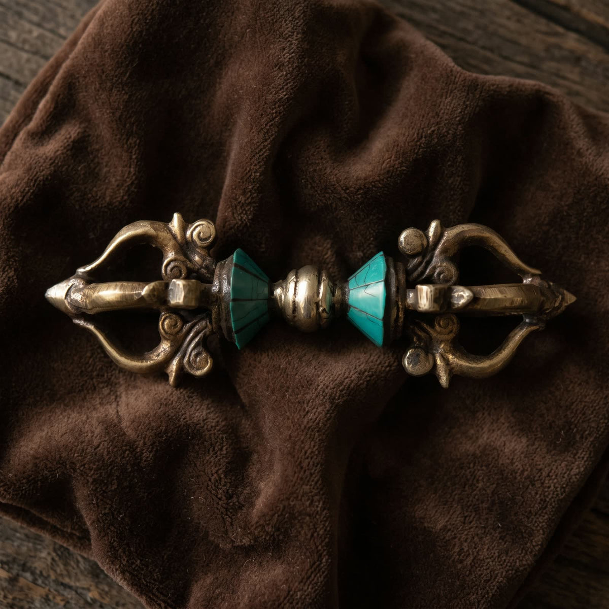 Top-down view of the five-pronged vajra with blue-green inlay on dark brown velvet