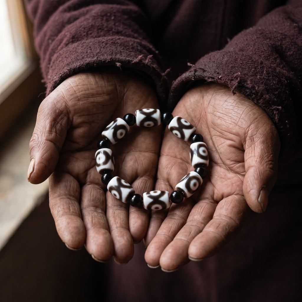 Elderly weathered hands holding the agate dzi and black agate bead bracelet in open palms