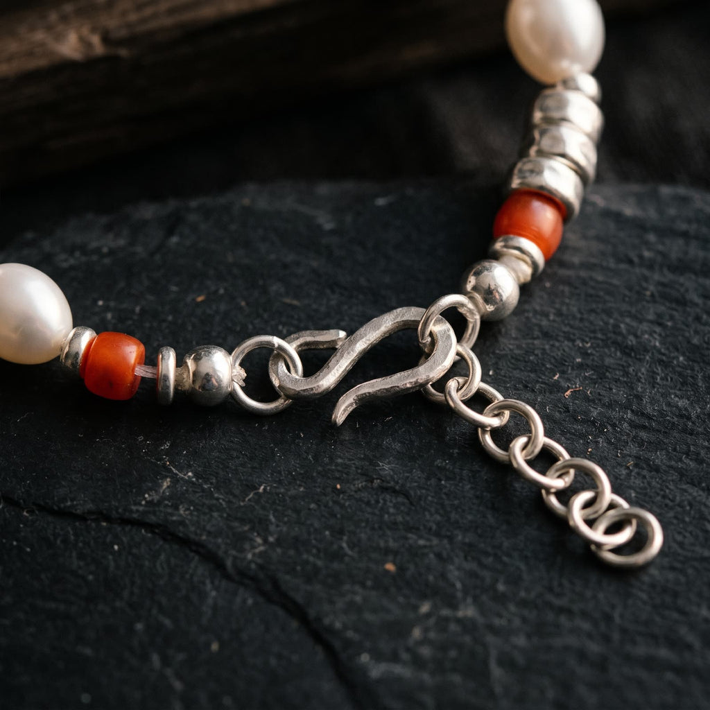 Close-up of the hammered 925 sterling silver S-hook caught in the extender chain, with red beads and hammered silver rondelles on either side