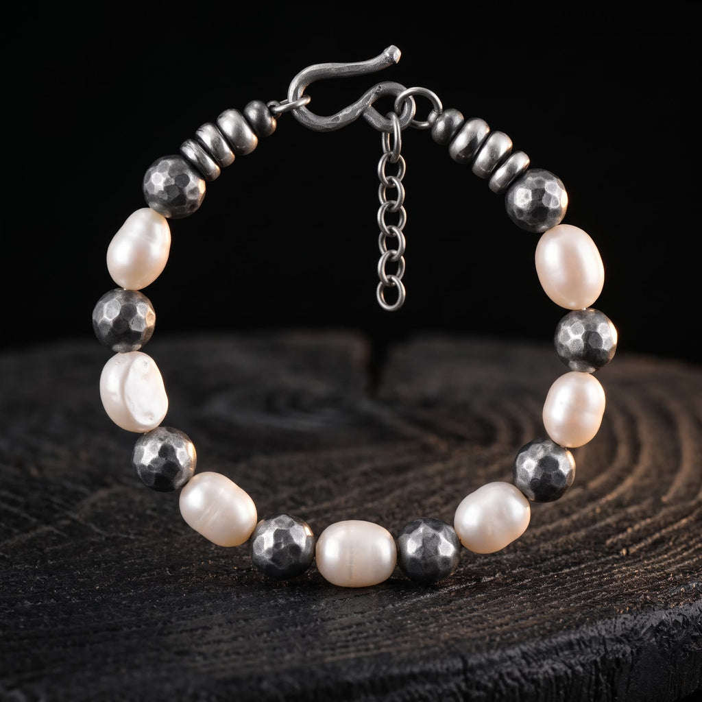Pearl and darkened hammered silver bead bracelet standing upright on a dark tree stump against black
