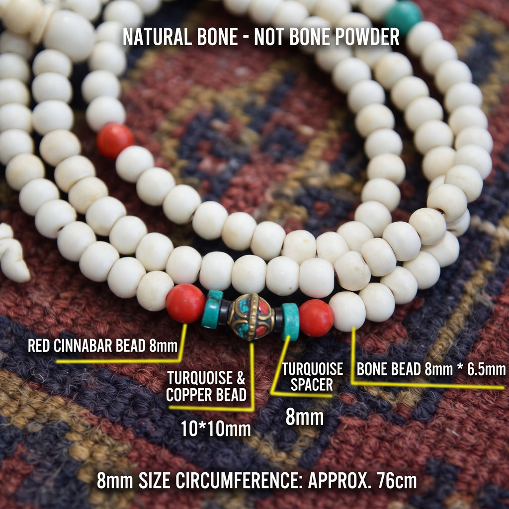 Yak bone mala close-up with red and turquoise beads around an inlaid copper bead, with size labels, on a red and blue rug