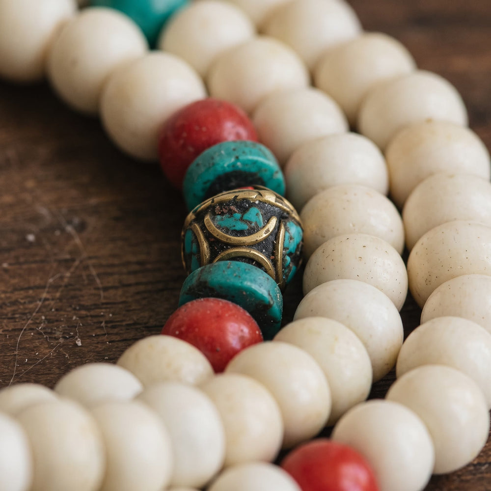 Close-up of the counter beads: red bead, turquoise disc, brass bead inlaid with turquoise, turquoise disc, red bead, between yak bone beads