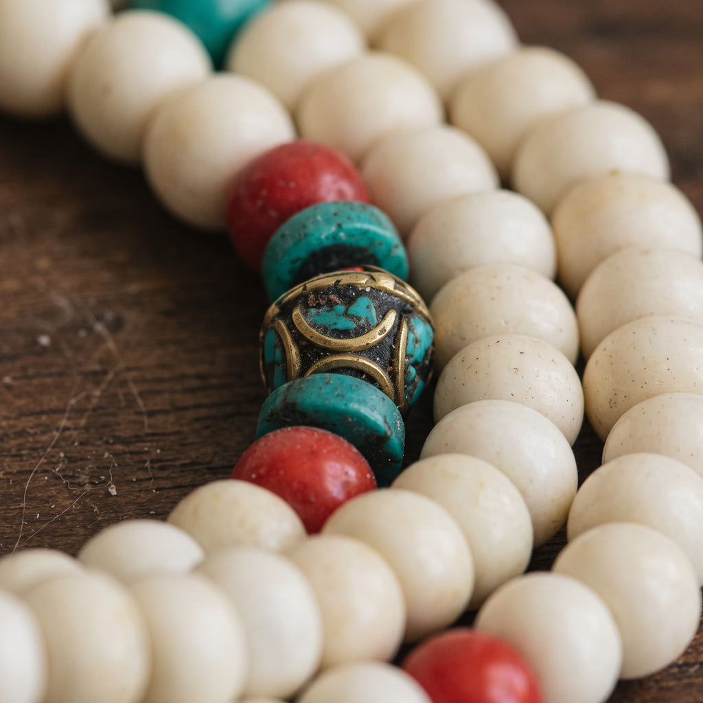 Close-up of the counter beads: red bead, turquoise disc, brass bead inlaid with turquoise, turquoise disc, red bead, between yak bone beads
