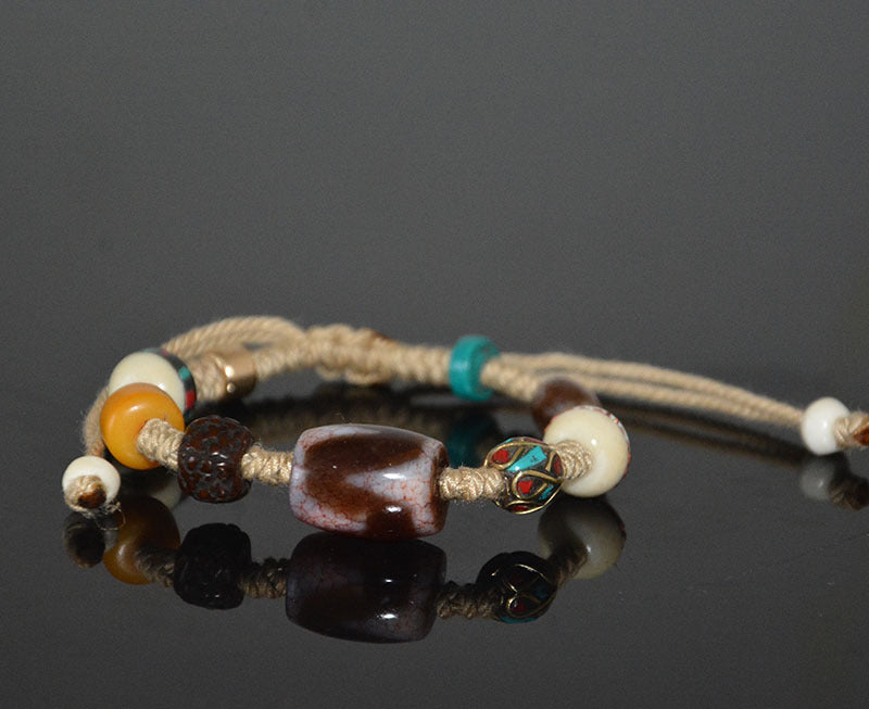 Supplier photo of the tiger-tooth dzi braided-cord bracelet, front view